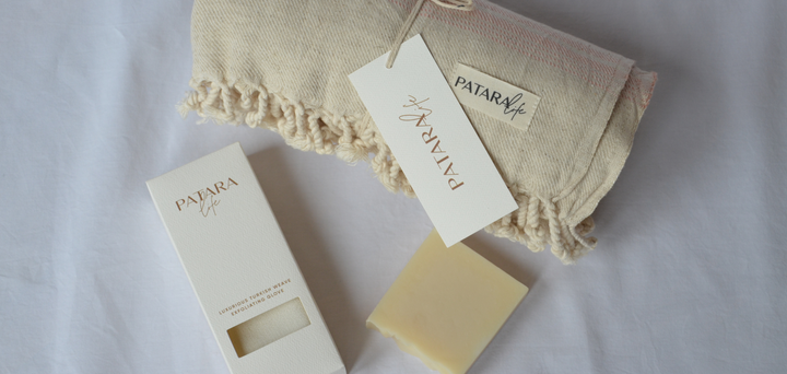A folded Peshtemal with olive oil soap and exfoliating glove as a gift bundle