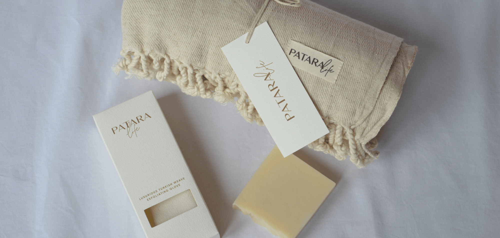 A folded Peshtemal with olive oil soap and exfoliating glove as a gift bundle