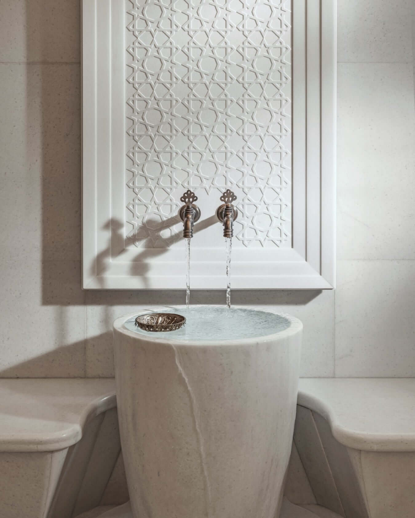 Turkish hamam spa ritual at home with a decorative stone basin and elegant wall design.