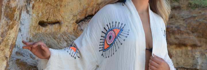 Woman wearing a stylish muslin cotton cover-up with eye-catching embroidery against a natural backdrop.