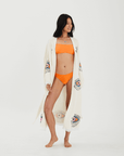 Model wearing an Evil Eye Robe over an orange bikini, showcasing its elegant design and vibrant patterns.