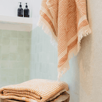 A "Kalkan" beach towel hanging in bathroom and another folded on top of stool