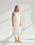 Elegant soft cotton dress with tied straps and leg slits, worn by a woman standing gracefully.