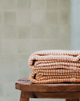 Two "Kalkan" beach towels folded on top of a stool