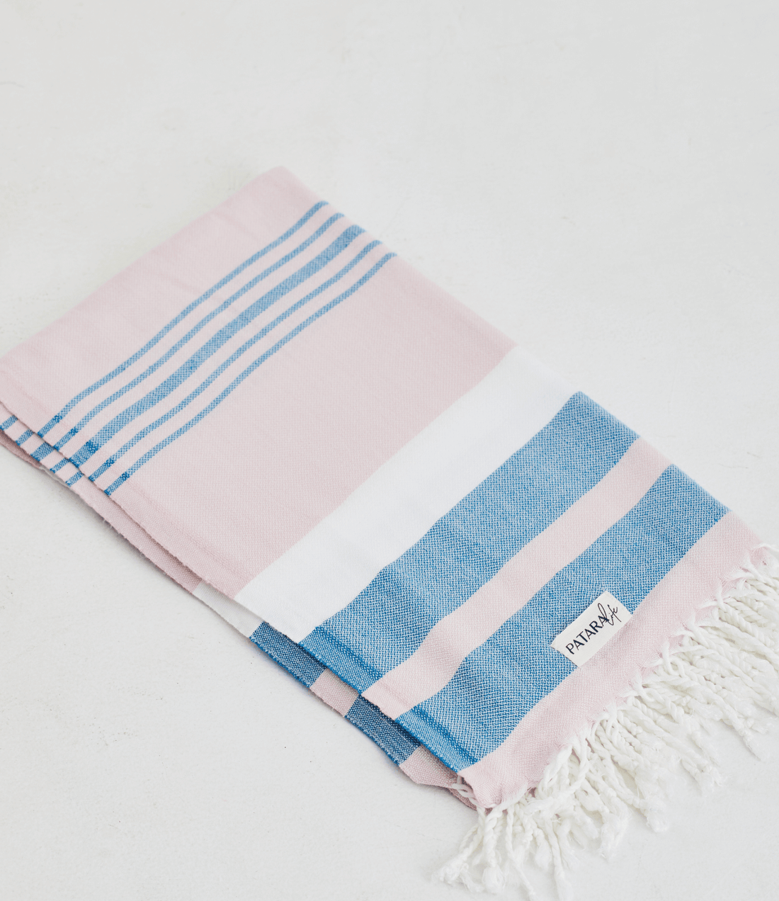 A lightweight peshtemal towel in light pink and blue