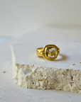 Green Amethyst Gold Ring resting on a stone surface, showcasing its luxurious design and sparkling gemstone.