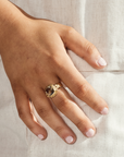 Person wearing a Green Amethyst Gold Ring, showcasing luxury and elegance on a hand with light pink nail polish.