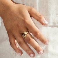Person wearing a Green Amethyst Gold Ring, showcasing luxury and elegance on a hand with light pink nail polish.