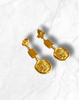Elegant gold disc earrings with a unique geometric design on a marble background.