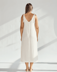 Back view of a woman wearing a soft cotton dress with tied straps, showcasing its elegant, breathable design.
