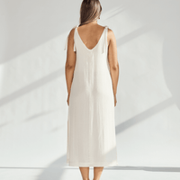 Back view of a woman wearing a soft cotton dress with tied straps, showcasing its elegant, breathable design.