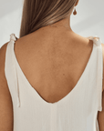 Back view of a soft cotton dress showcasing tied straps and a deep v-neckline, highlighting its elegant design.