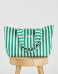 Herringbone woven linen tote bag in Green stripe on top of stool