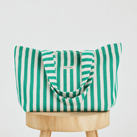 Herringbone woven linen tote bag in Green stripe on top of stool