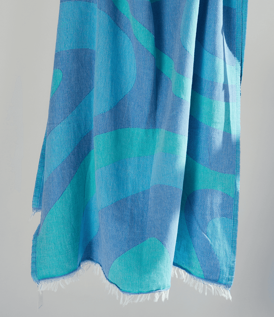 Turkish Beach Towel with an abstract wave design in shades of blue and turquoise, showcasing a vibrant coastal aesthetic.