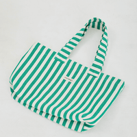 Herringbone woven linen tote bag in Green stripe layed flat on floor