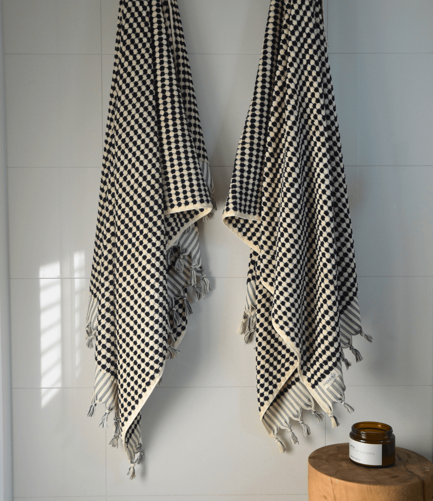 Elegant black and white Turkish cotton bath towels hanging on a wall, showcasing artisanal craftsmanship and luxury.