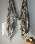 Elegant black and white Turkish cotton bath towels hanging on a wall, showcasing artisanal craftsmanship and luxury.