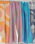 Collection Turkish Beach Towels in vibrant colors and abstract wave designs, showcasing Turkish Cotton fabric.