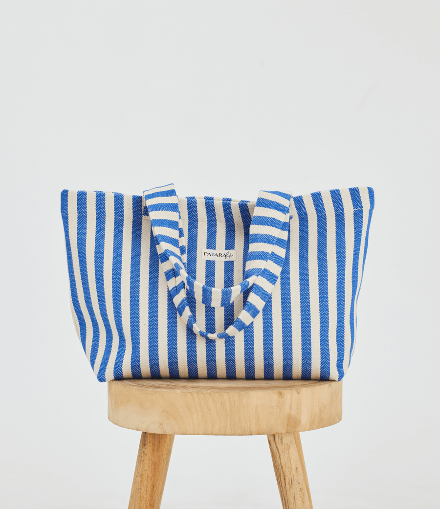 Herringbone woven linen tote bag in Blue stripe on top of stool