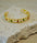 Gold bracelet with colorful stones on a textured stone surface