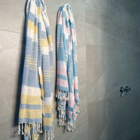 Two lightweight peshtemal towels hanging on bathroom wall