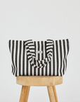 Herringbone woven linen tote bag in Color: Black stripe on top of stool