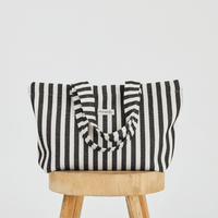Herringbone woven linen tote bag in Color: Black stripe on top of stool