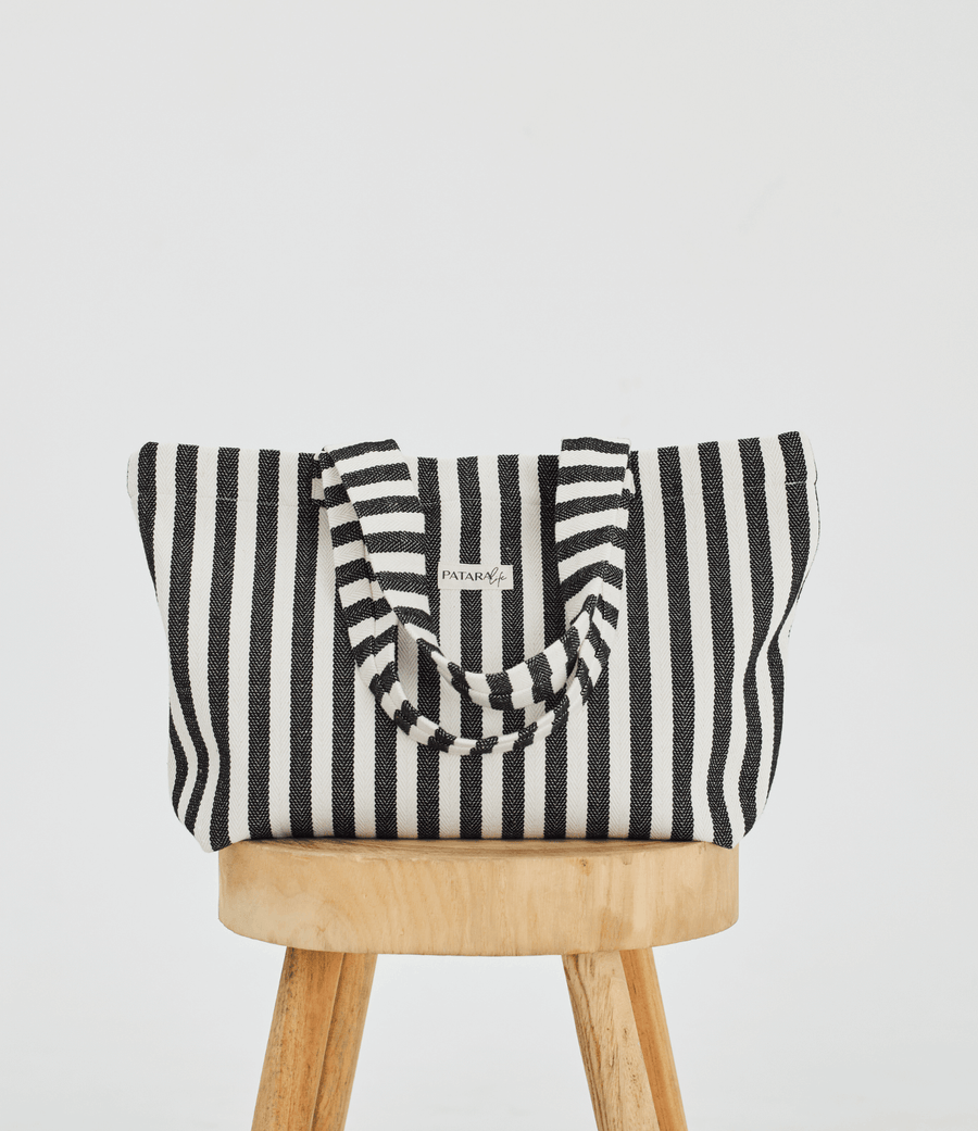 Herringbone woven linen tote bag in Color: Black stripe on top of stool