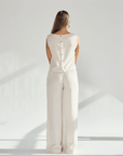 Back view of a woman in a beige linen wide leg and crop top set, showcasing buttons and a chic silhouette.