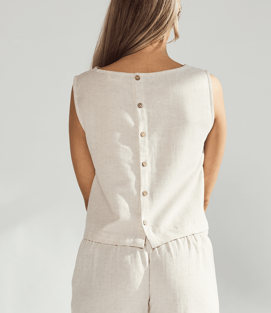 Back view of a woman's linen crop top featuring button details and a relaxed fit.