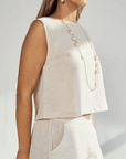 Woman wearing a beige linen crop top with a pearl necklace, showcasing a stylish and comfortable outfit.