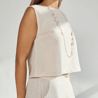 Woman wearing a beige linen crop top with a pearl necklace, showcasing a stylish and comfortable outfit.