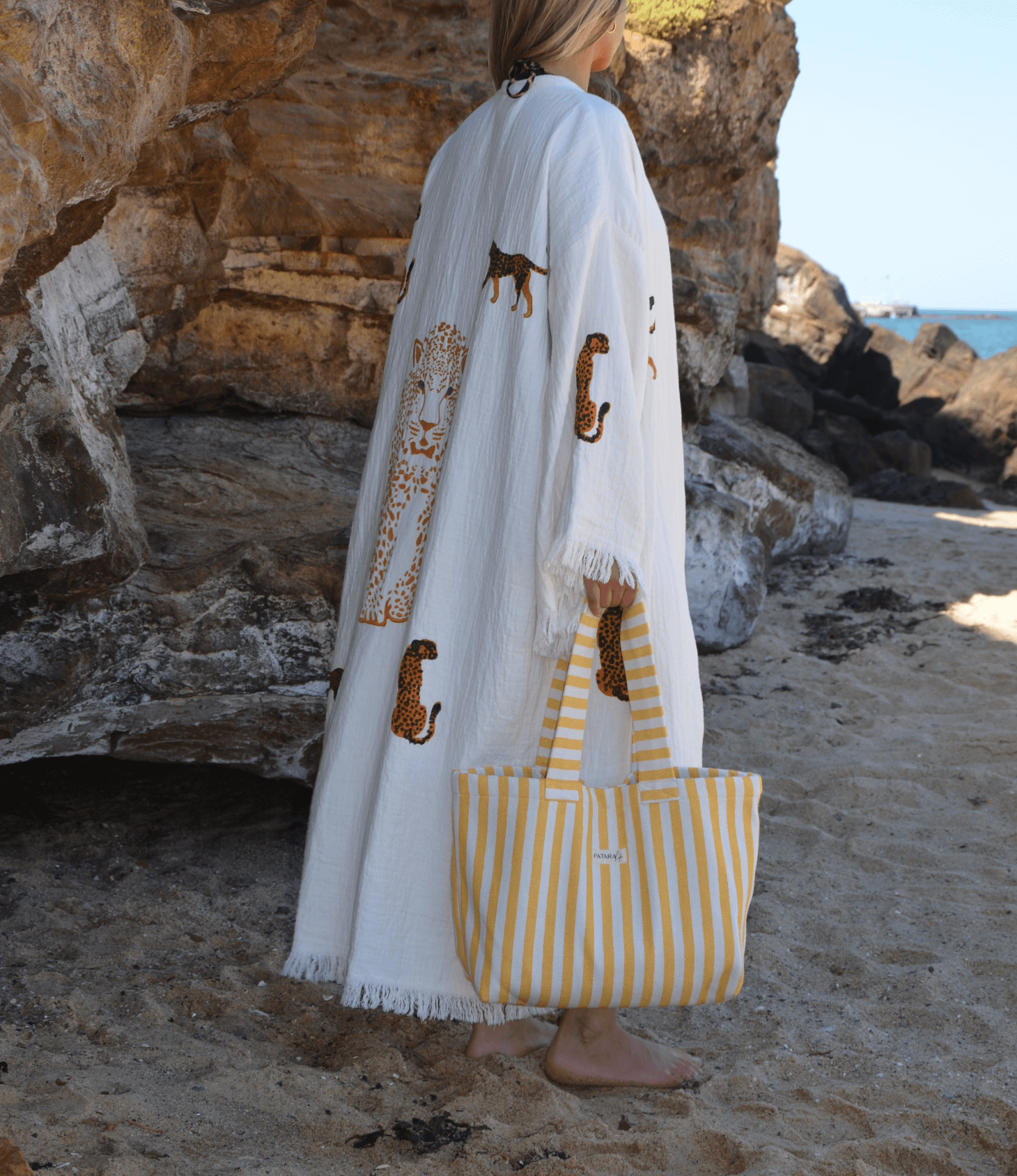 Woman at the beach holding a yellow beach tote bag