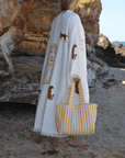 Woman at the beach holding a yellow beach tote bag