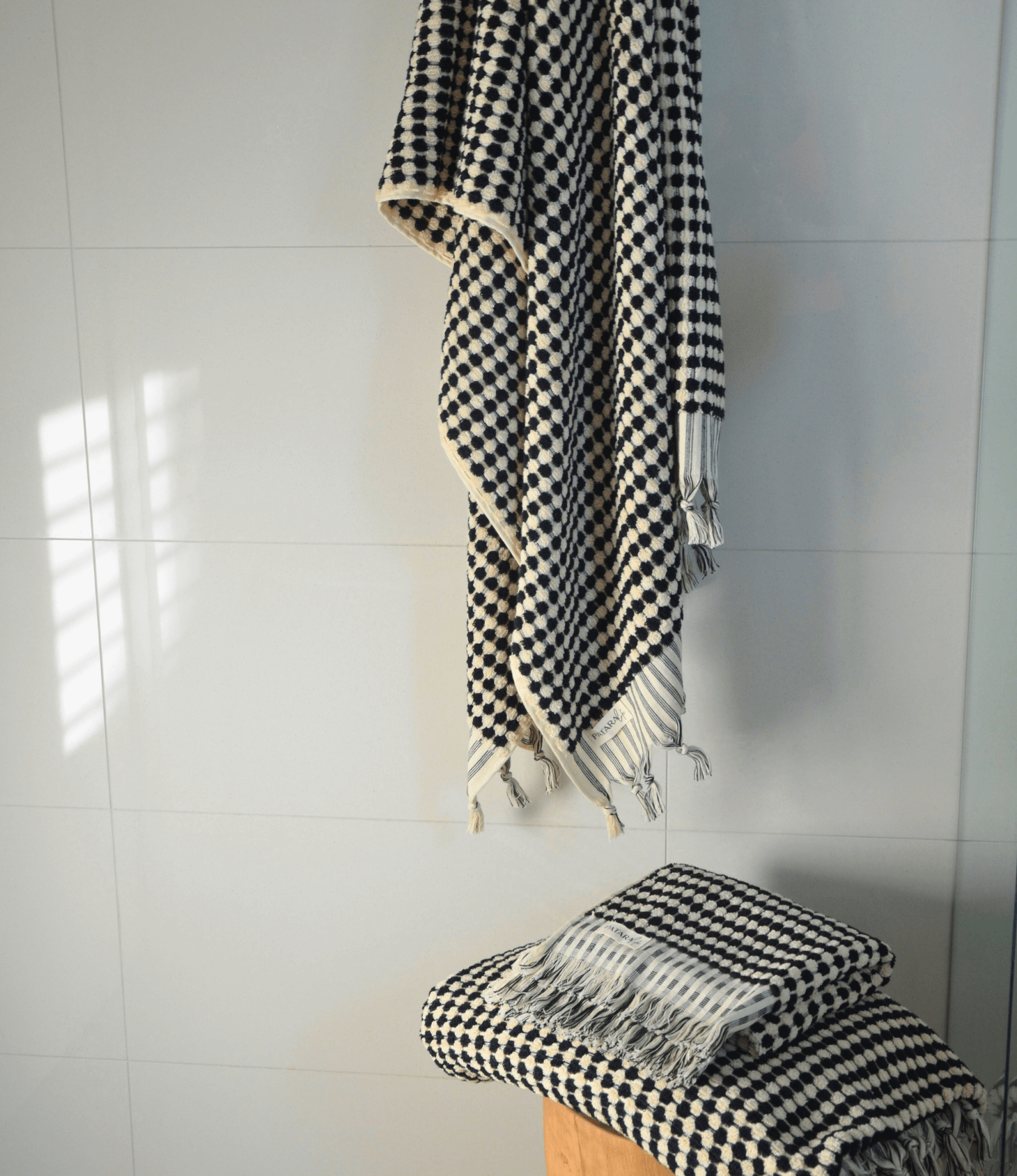 Black and white checkered Turkish cotton bath towel draped and folded, showcasing luxurious texture and design.