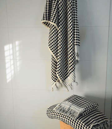 Black and white checkered Turkish cotton bath towel draped and folded, showcasing luxurious texture and design.