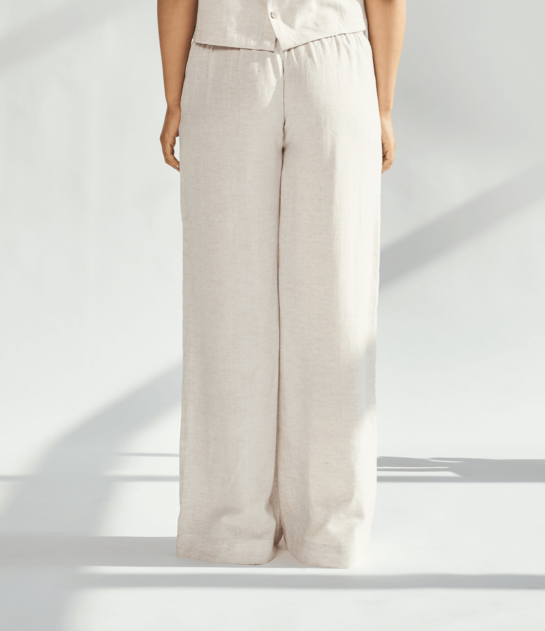 Back view of elegant linen wide leg pants in light beige, showcasing a flowing silhouette and comfortable fit.