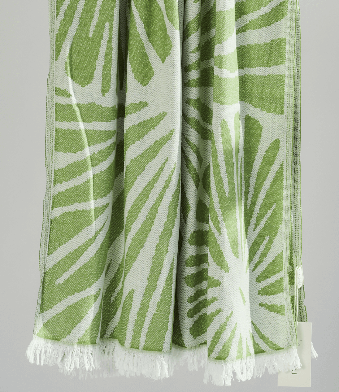 Radiance Turkish Beach Towel featuring a green sunburst pattern, made from soft organic cotton with fringe detail.