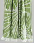 Radiance Turkish Beach Towel featuring a green sunburst pattern, made from soft organic cotton with fringe detail.