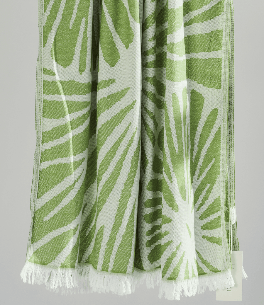 Radiance Turkish Beach Towel featuring a green sunburst pattern, made from soft organic cotton with fringe detail.