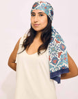 Woman wearing a patterned headscarf on a plain background
