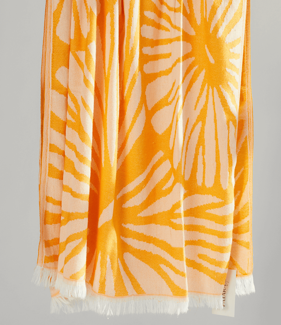 Radiance Turkish beach towel featuring a sunburst pattern in golden yellow and soft orange hues.