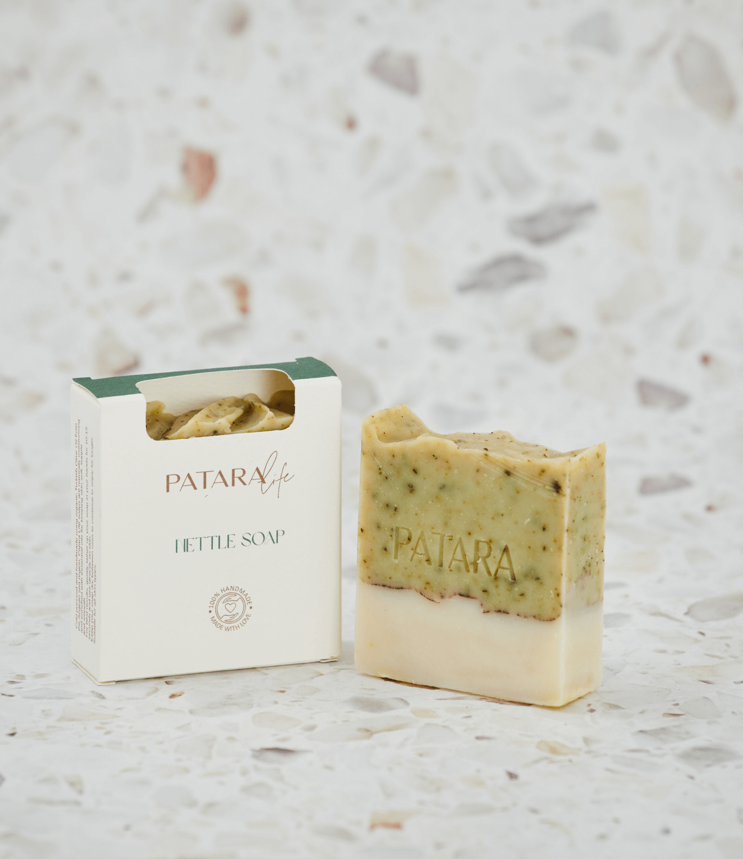 Nettle cold pressed olive oil soap bar by PATARA, with packaging and a slice displayed on a textured background.