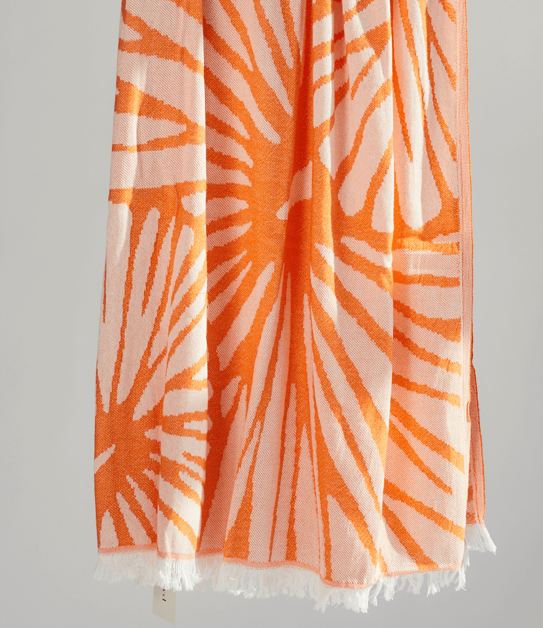 Radiance Turkish Beach Towel showcasing a sunburst pattern in golden yellow and soft orange, made from organic cotton.