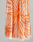 Radiance Turkish Beach Towel showcasing a sunburst pattern in golden yellow and soft orange, made from organic cotton.