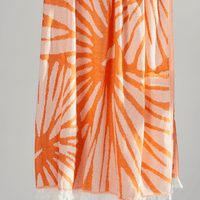 Radiance Turkish Beach Towel showcasing a sunburst pattern in golden yellow and soft orange, made from organic cotton.