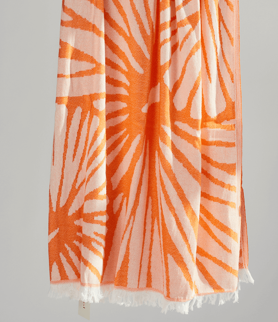 Radiance Turkish Beach Towel showcasing a sunburst pattern in golden yellow and soft orange, made from organic cotton.