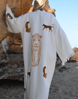 Woman wearing a leopard print muslin cotton robe on a beach, showcasing intricate animal designs.
