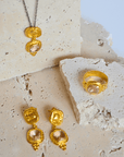 Gold jewelry set with pink gemstones on a textured stone surface.